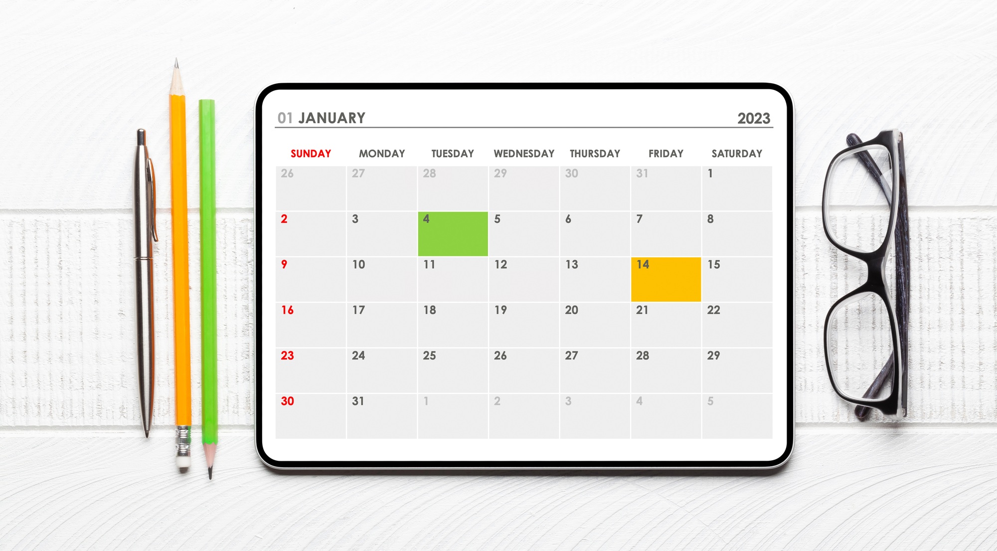 Tablet with calendar app, eyeglasses and office supplies
