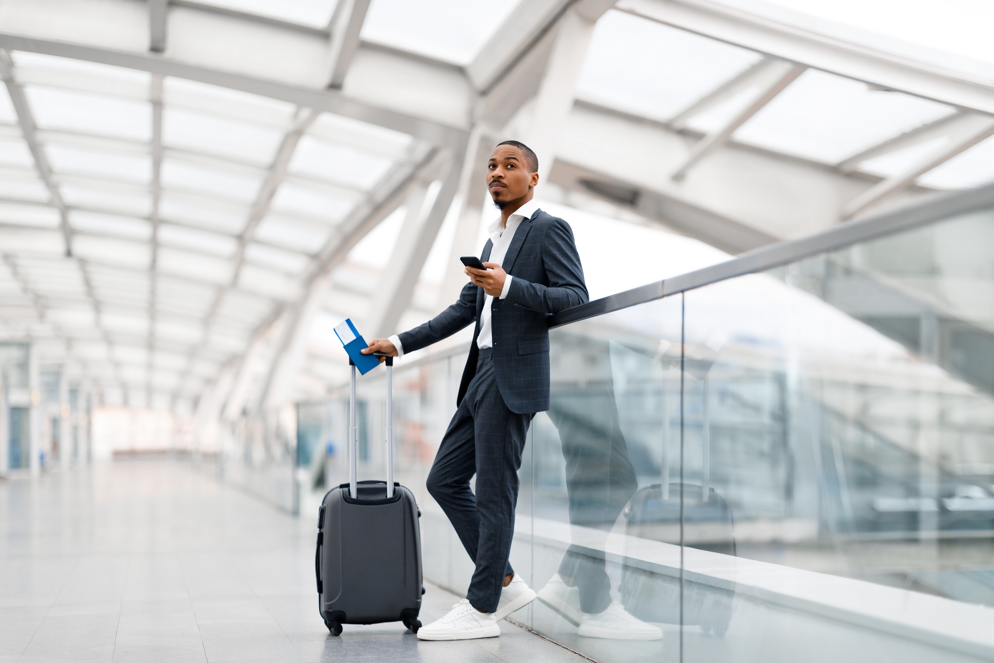 Waiting For Flight. Young Black Businessman Using Smartphone In Airport