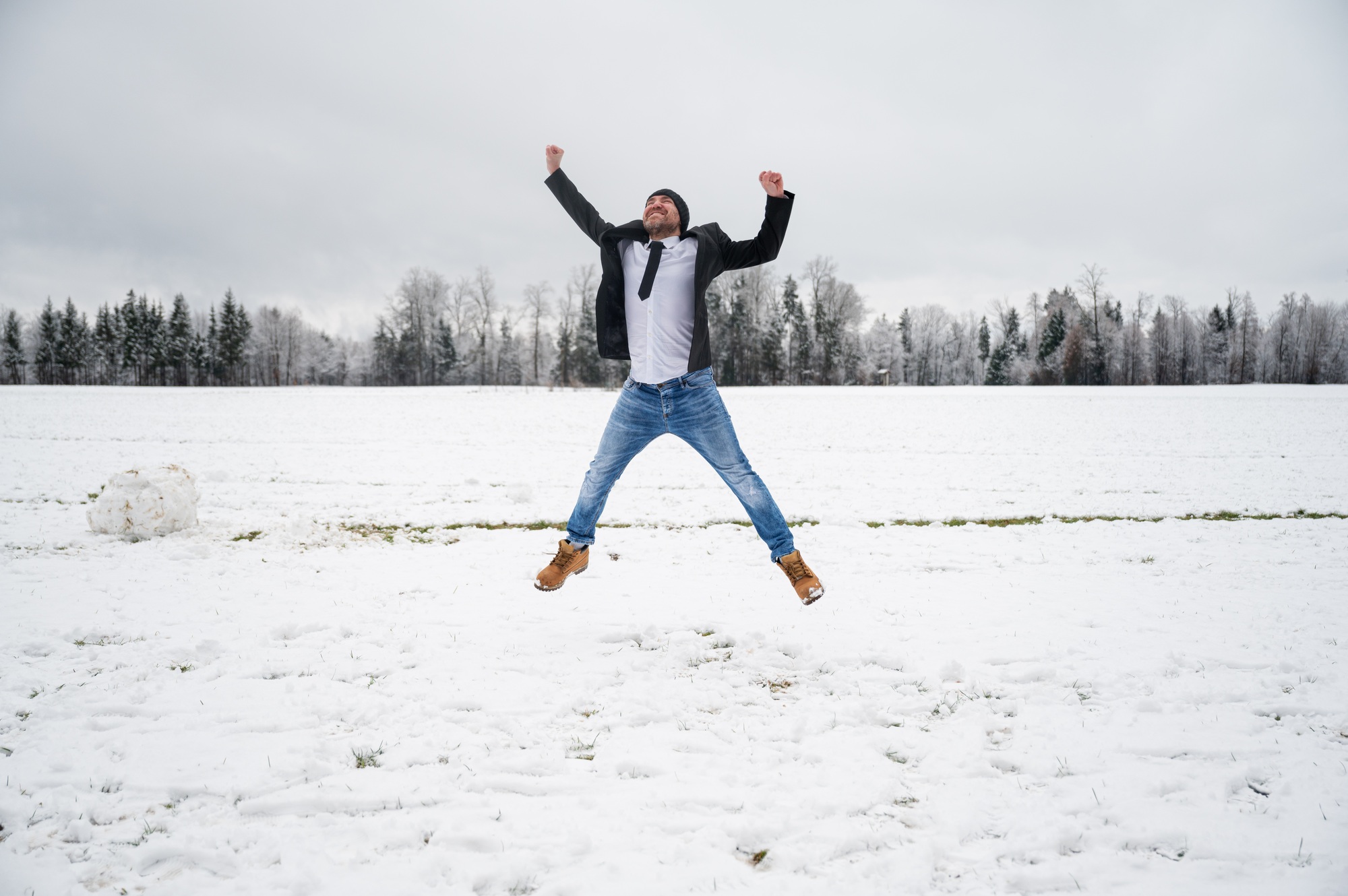 Young man jumping with joy in snowy nature